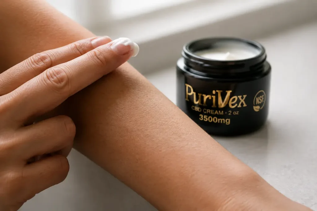 Cream on a fingertip about to be worked into the skin, jar beside it